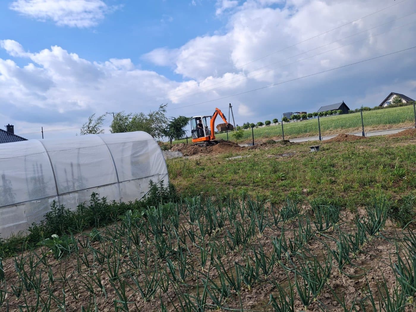 Prace ziemne pod ogrodzenie — koparka przy wykopach pod słupki
